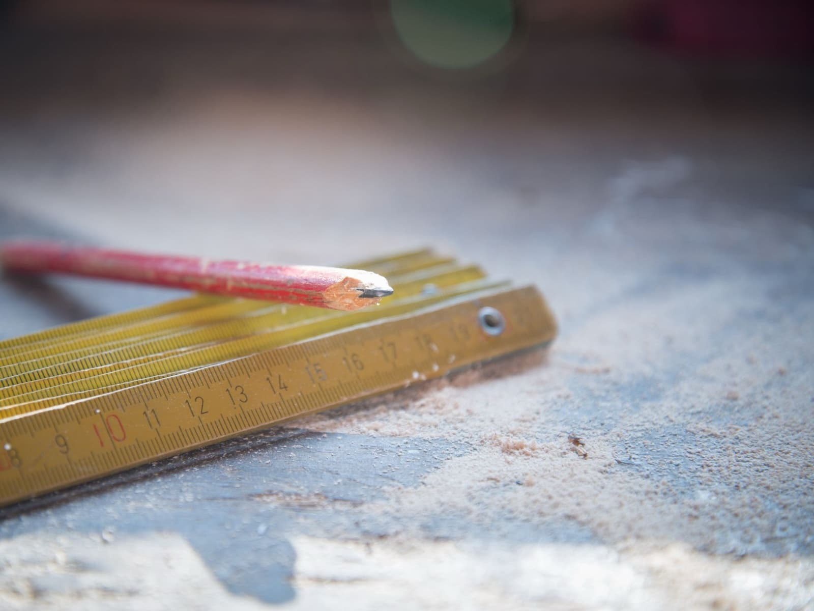 Bauzeichnung mit Maßstab und Bleistift auf einer Holzplatte, daneben ein aufgeschlagener Ordner